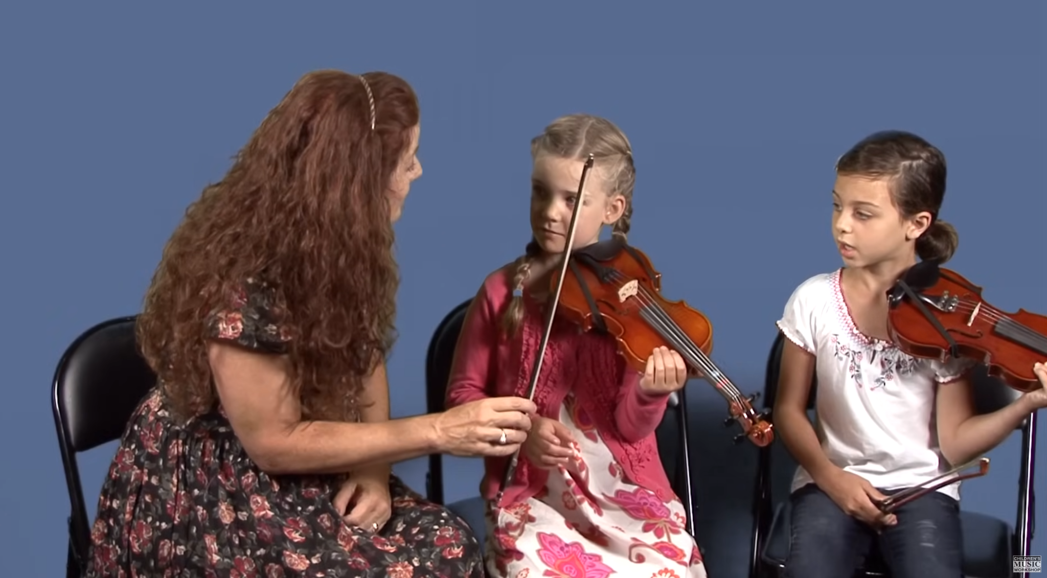 Teacher working with two very young beginning violin students